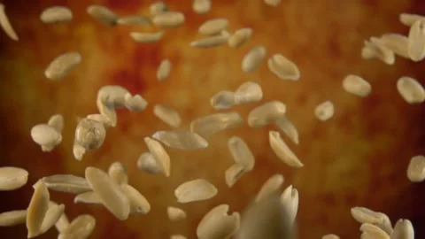 Peeled tasty peanuts are bouncing on a yellow ochre background Stock Footage 149893171