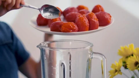 Peeled tomatoes put to a blender. Red tomato falling into a glass bowl. Cooking Stock Footage 135236791