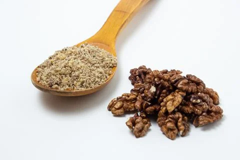 Peeled walnuts and ground walnuts on a white background. A wooden spoon full of  Stock Photos