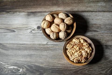 Peeled walnuts and nuts in a  shell in walnut wooden bowl on a wooden backg.. Stock Photos