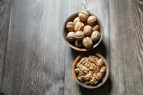 Peeled walnuts and nuts in a  shell in walnut wooden bowl on a wooden backg.. Stock Photos