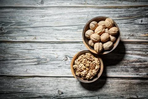 Peeled walnuts and nuts in a  shell in walnut wooden bowl on a wooden backg.. Stock Photos