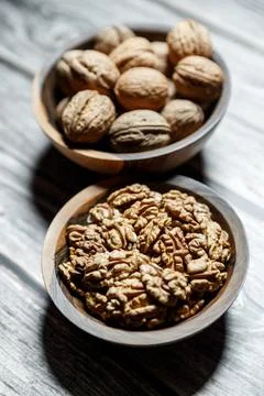 Peeled walnuts and nuts in a  shell in walnut wooden bowl on a wooden backg.. Stock Photos