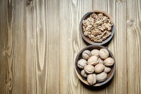 Peeled walnuts and nuts in a  shell in walnut wooden bowl on a wooden backg.. Stock Photos
