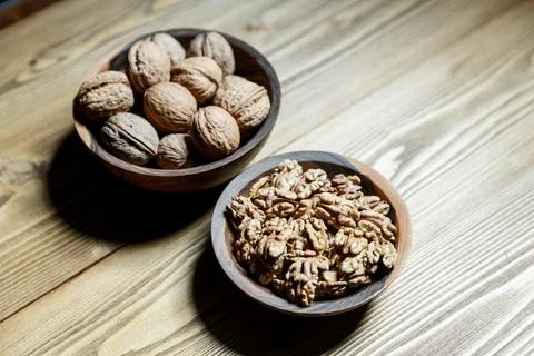 Peeled walnuts and nuts in a  shell in walnut wooden bowl on a wooden backg.. Stock Photos