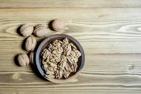 Peeled walnuts and nuts in a  shell in walnut wooden bowl on a wooden backg.. Stock Photos