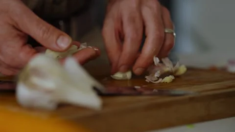 Peeling and cutting of garlic on chopper board by adult male chef. Stock Footage 301682387