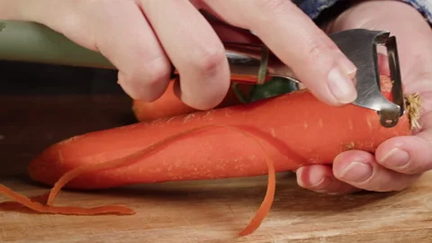 Peeling carrot with grater close-up. Preparing some vegetables for cooking Stock Footage 260417537