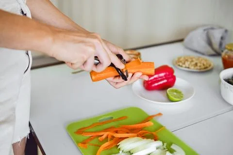 Peeling carrots in a bright kitchen while preparing a healthy meal with fre.. Foto stock