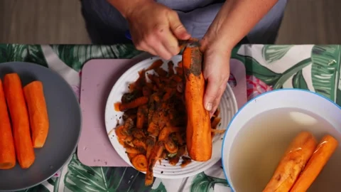 Peeling carrots on a patterned kitchen counter Stock Footage 343532295