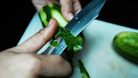 Peeling a Cucumber with a Knife, Close-up of hands peeling a cucumber with .. Stock Footage 304978459