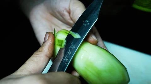 Peeling a Cucumber with a Knife, Close-up of hands peeling a cucumber with .. Stockbeeldmateriaal 304978547
