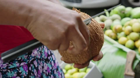 Peeling the fresh coconut fruit at the local market in bright daylight Stock Footage 321357991