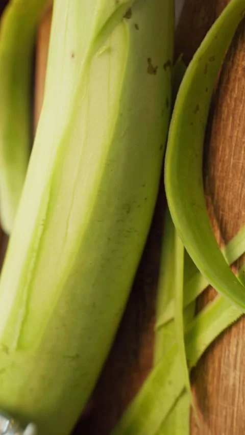 Peeling of a fresh locky or Bottle gourd on a wooden chopping board. Stock Footage 283363408