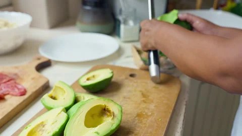 Peeling a fresh ripe avocado with a kitchen knife, close up Stock Footage 341438243