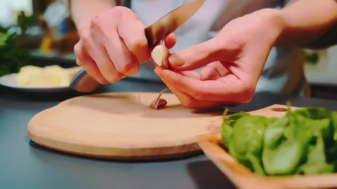 Peeling garlic with a knife on the kitchen table Stock Footage 249791164
