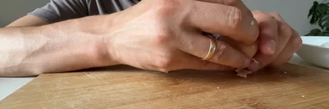Peeling hard boiled egg by hand on wooden cutting board Stock Footage 337482450