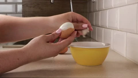 Peeling hard-boiled egg over kitchen counter with yellow bowl. close-up of hands Stock Footage 317108261