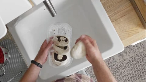 Peeling mushrooms over a kitchen sink. Male hands use a knife and fingers t.. Video stock 280034491