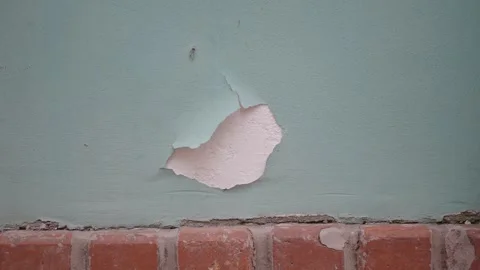 Peeling paint reveals old plaster texture on exterior wall near brickwork. Stock Footage 332108936