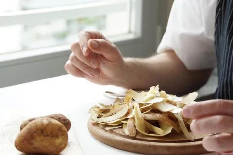 Peeling potatoes at home in the kitchen Stock Photos