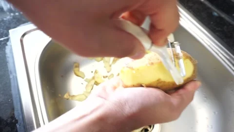 Peeling potatoes at the kitchen sink Stock Footage 257544544