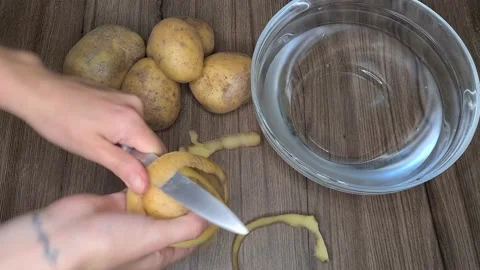 Peeling Potatoes With A Knife. Fresh Vegetables On The Table. 動画素材 165504537