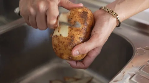 Peeling potatoes over a kitchen sink. Stock Footage 106852845