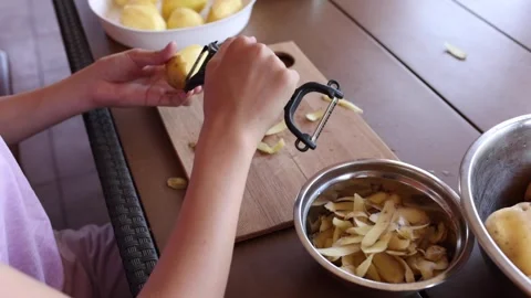 Peeling potatoes in a rustic kitchen for a homemade meal Stock Footage 297358654