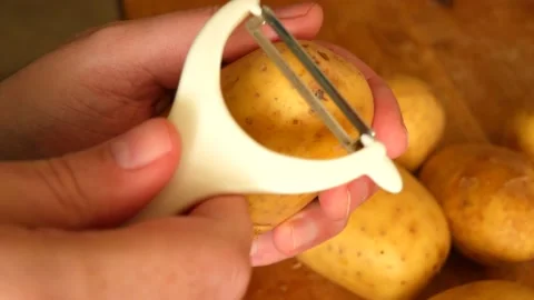 Peeling potatoes with a white peeler Stock Footage 135876475