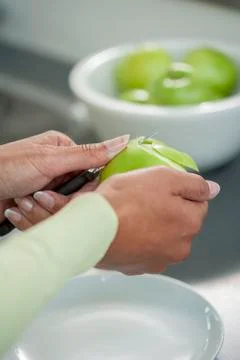 Peeling skin off of green apple using a paring knife Stock Photos