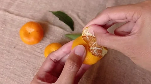 Peeling the small orange on a brown table Stock Footage 149709090