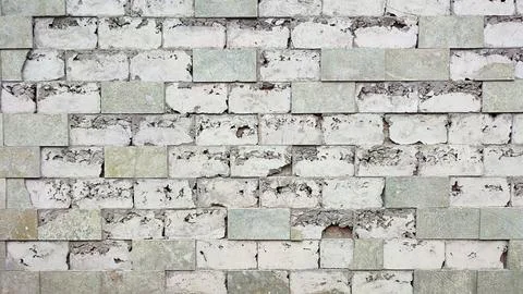 The peeling square stone wall on the side of the road is perfect for the backgro Stock Photos