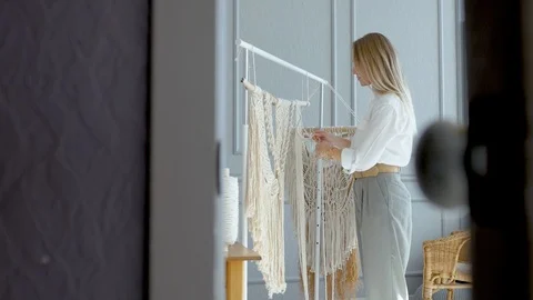 Peeping at the doorway behind a macrame weaving master Stock Footage 120982858