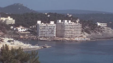 Peguera, Mallorca - 1977: Buildings under construction overlooking beach and sea Stock Footage 308714341