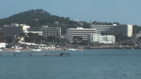 Peguera, Mallorca - 1977: Panoramic view revealing waterfront buildings and sea Stock Footage 308714410