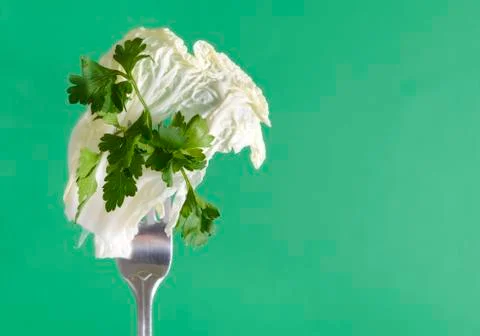 Peking cabbage leaf, lettuce leaf and parsley sprig on a fork on a green back Stock Photos
