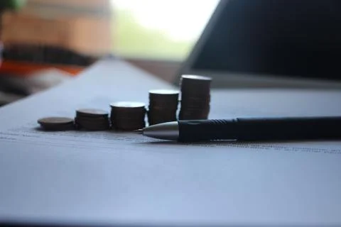 Pen and agreement , stack of coin reminding growing diagram and laptop comput 库存照片