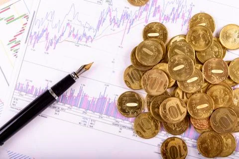 Pen and coins on the background of graphs and charts Foto stock