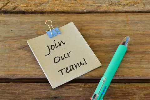 Pen and memo note written with JOIN OUR TEAM! over wooden background. Stock Photos