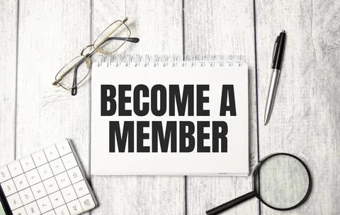 Pen and a white notebook with the text BECOME A MEMBER on wooden background Stock-Fotos