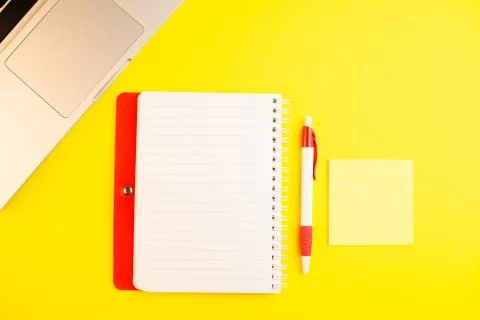 Pen, laptop, notepad planner and note stick on yellow background. Flat lay. C Stock Photos