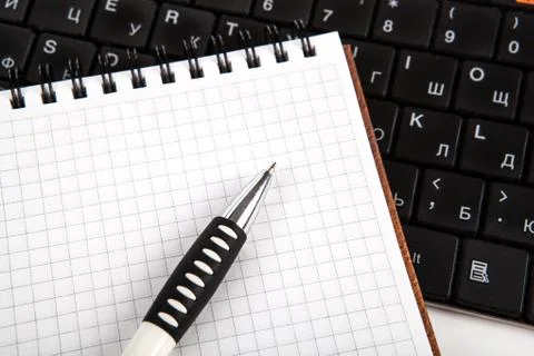 Pen on a notebook into a cell and keyboard Stock Photos