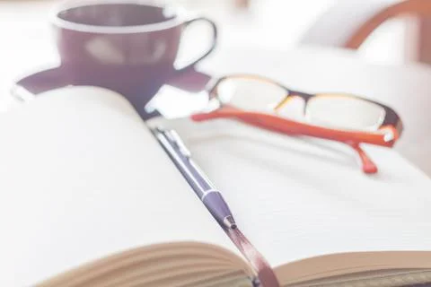 Pen, notebook coffee cup and eyeglasses on the wooden table Stock Photos
