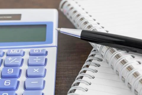 Pen, notepad, and calculator on the wooden table Stock Photos