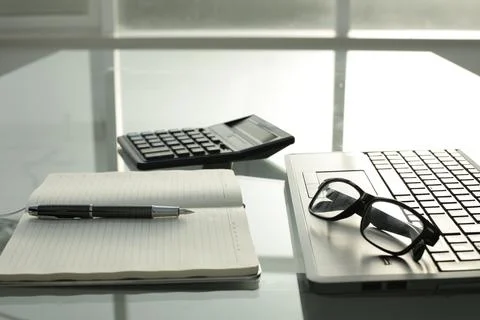 Pen notepad calculator glasses notebook on glass table Stock-Fotos