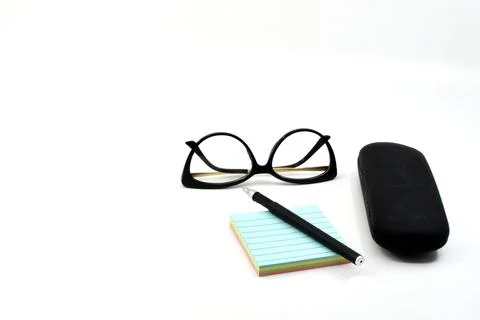 Pen on a pad of reminder notes with a pair of women's glasses and a glasses case Stock Photos