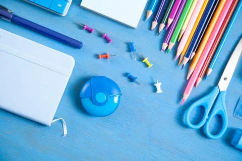 Pen, pencils, note, eraser scissors, sticky notes on the blue background. Stock Photos