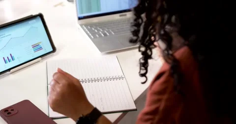 Pen is pointing at laptop spreadsheet with tablet charts on desk, notebook Stock Footage 341865083