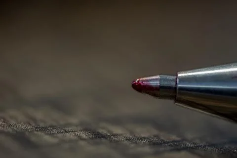 A pen with a red tip is on a dark surface 스톡 사진